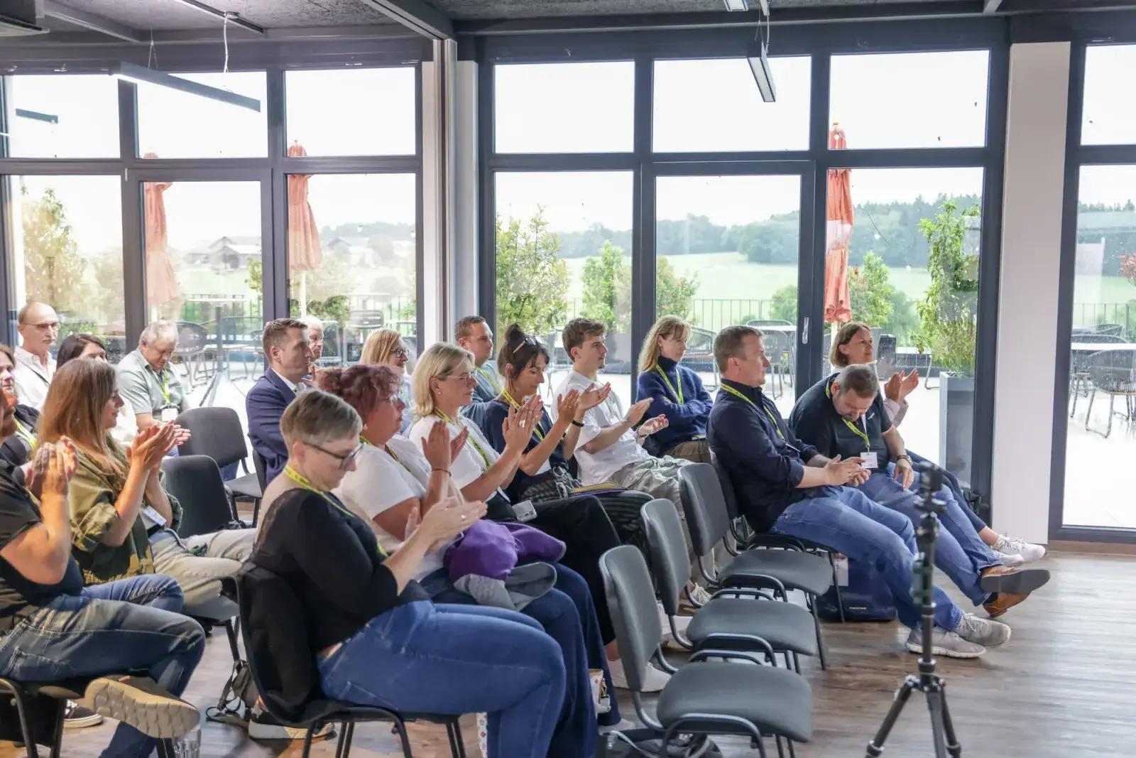 Publikum applaudiert, im Hintergrund die Fensterfront zur Terrasse