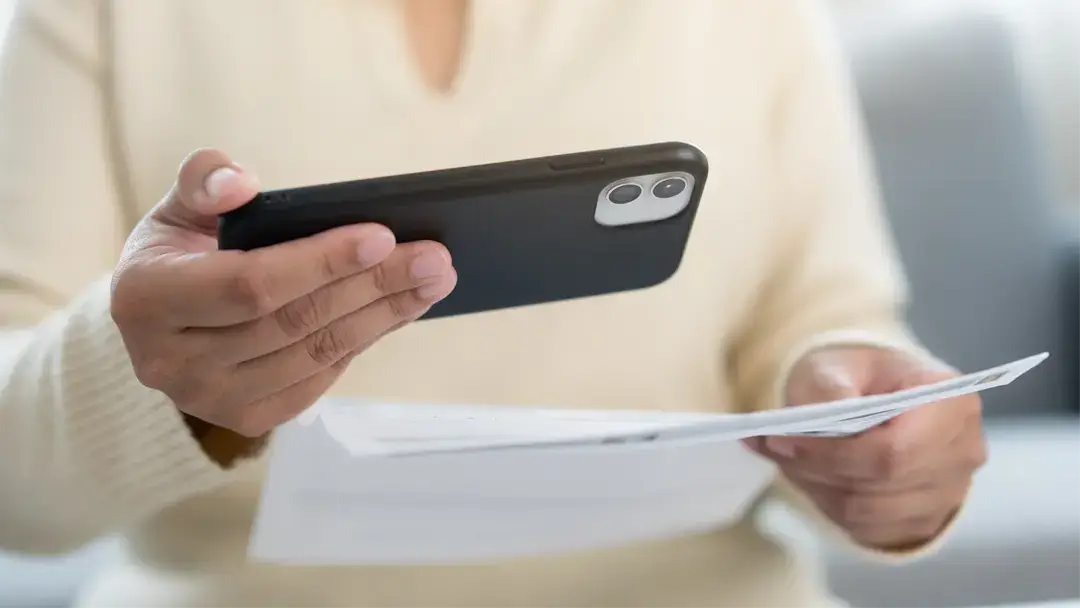 Frau fotografiert eine Rechnung mit ihrem Smartphone