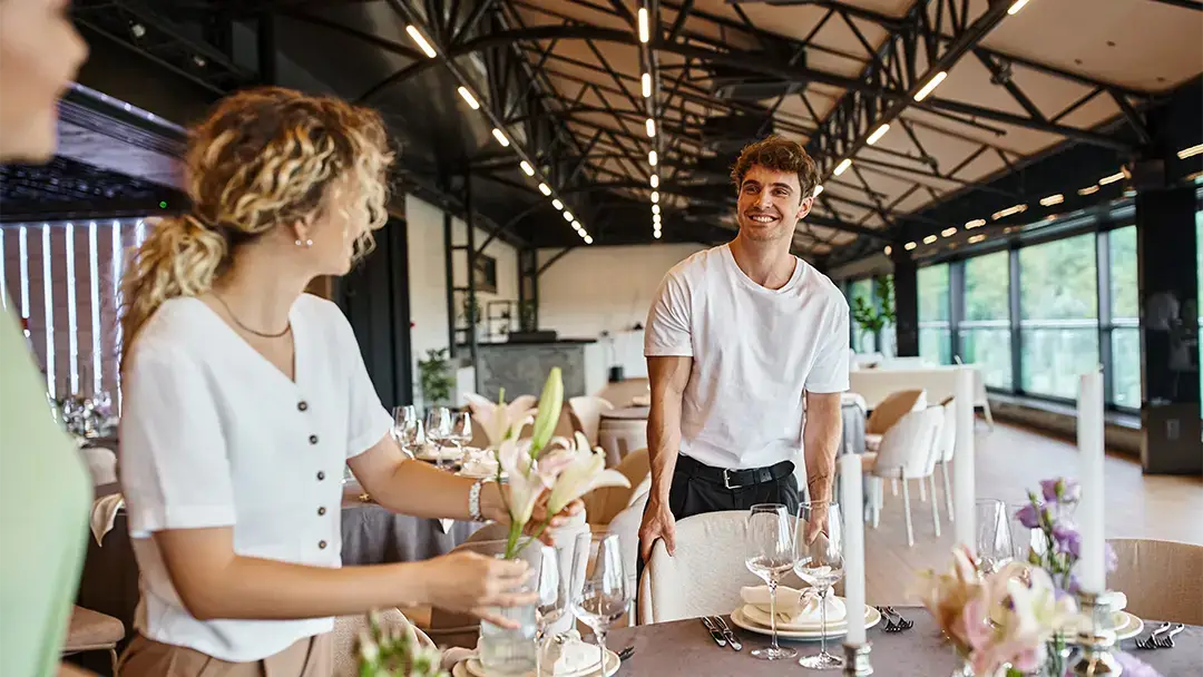 Mitarbeiter eines kleinen Veranstaltungsunternehmens beim Schmücken eines Tisches