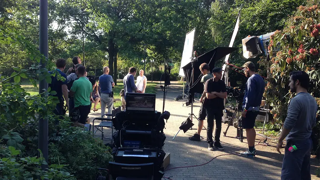 Filmteam mit Kamera und Scheinwerfern bei einem Dreh im Park